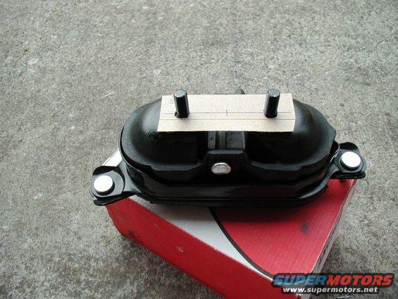 Black painted automotive component, possibly a differential or pump cover, with two studs, in box
