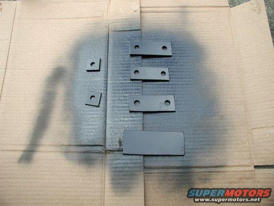 Metal brackets being spray painted gray on cardboard