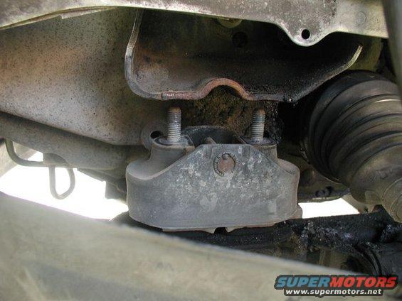Engine mount with two bolts attached to a metal bracket, showing a CV boot and suspension components