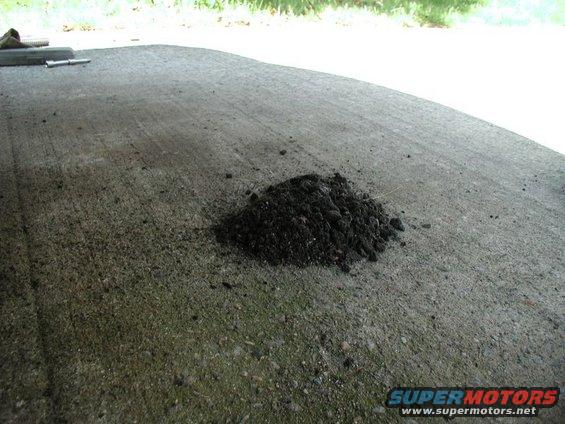 Pile of dirt on a concrete surface with grass in the background