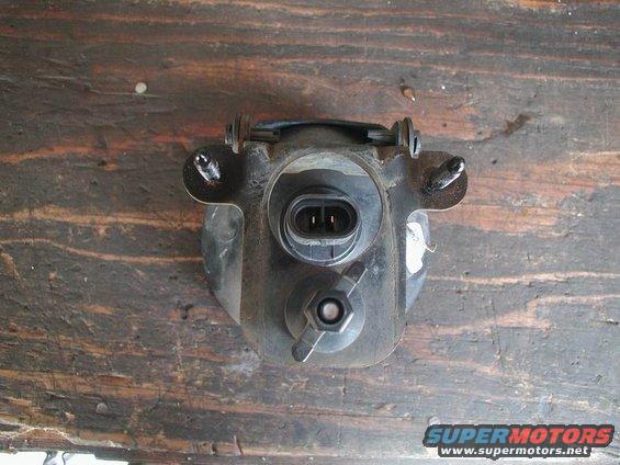 Fog light assembly with electrical connector and adjustment knob, mounted on a wooden surface