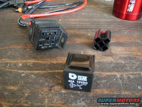 Black automotive relay and two other small electronic components on a wooden surface
