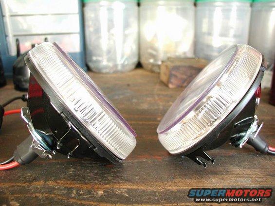 Two car headlights, possibly for a 2002 Pontiac Grand Prix, resting on a wooden surface