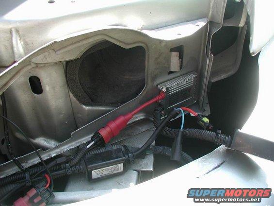 Mechanic working on car's front end, possibly installing fog lights