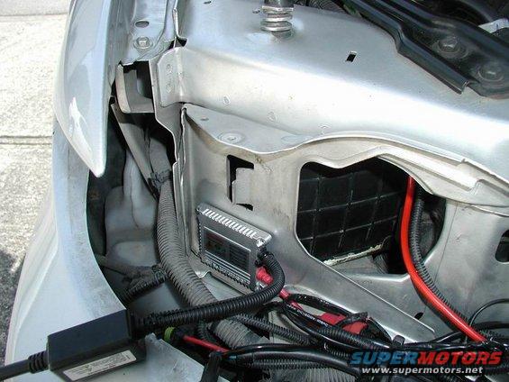 White car fender liner with exposed wiring and black hoses
