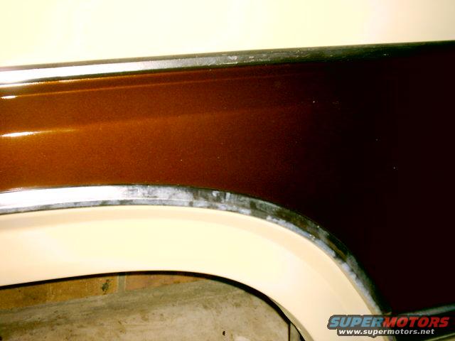 Close-up of a vehicle's rear fender with brown and cream paint, showing trim detail