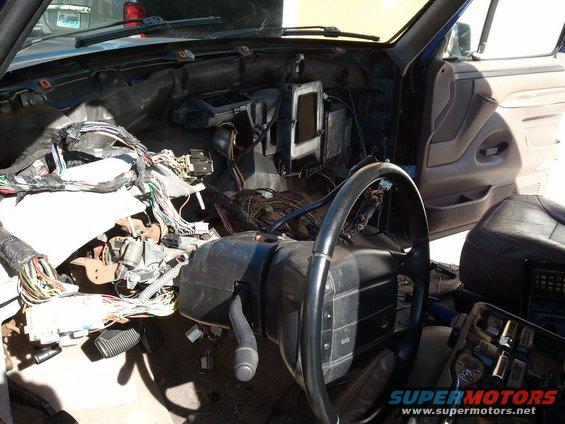 Disassembled dashboard of a 1994 Ford Bronco with exposed wiring and steering wheel