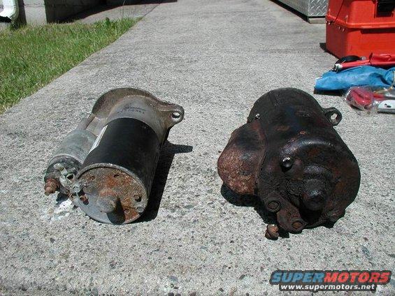 Two starters on concrete; one is silver and black, the other is heavily rusted and dark