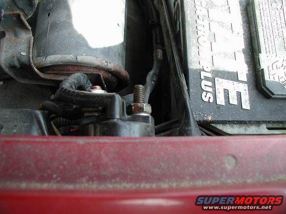 Close-up of a starter motor and a car battery with some wiring