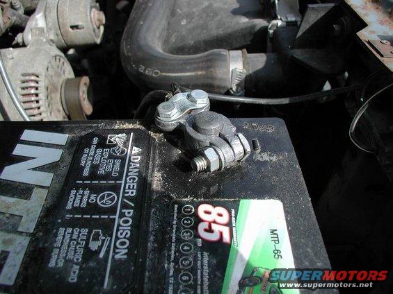 Close-up of a car battery terminal and part of an alternator