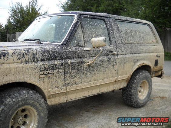 Mud-covered 1990 Ford Bronco, side view. Bronco badge visible on fender