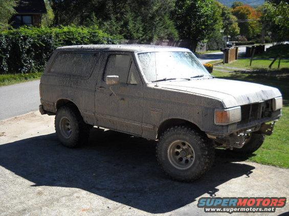 Mud-covered Ford Bronco, 3q-front view, missing grille and bumper