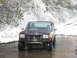 1990 Ford Bronco - A Ford Bronco navigates a snowy, wet road in this front-facing shot.