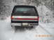 1990 Ford Bronco - This Ford Bronco, seen from the rear, is driving through a snowy wooded area.