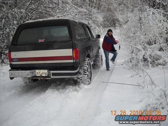 1990 Ford Bronco rear view in snowy woods, person standing next to it