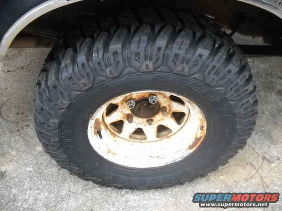 Tire and rusty white wheel on a vehicle, close-up