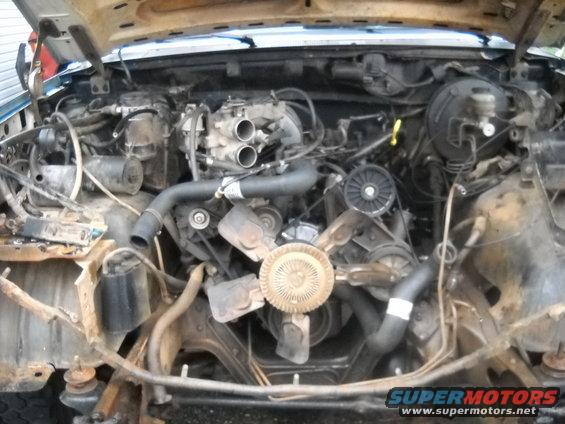 Engine bay of a 1990 Ford Bronco with the hood open, showing the engine and surrounding components
