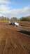 1995 Ford Bronco - A white pickup truck is stuck deep in mud on a farm, with a person standing in the open driver's side door.