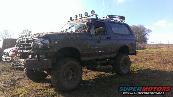 Mud-covered 1995 Ford Bronco with roof rack and off-road lights