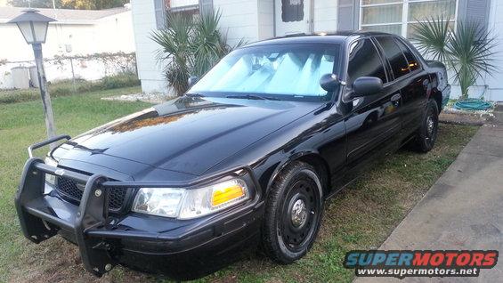 Black 2004 Ford Crown Victoria police car with a push bumper parked on grass