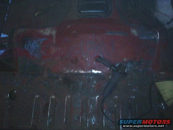 Red vehicle interior floor with rust and an angle grinder