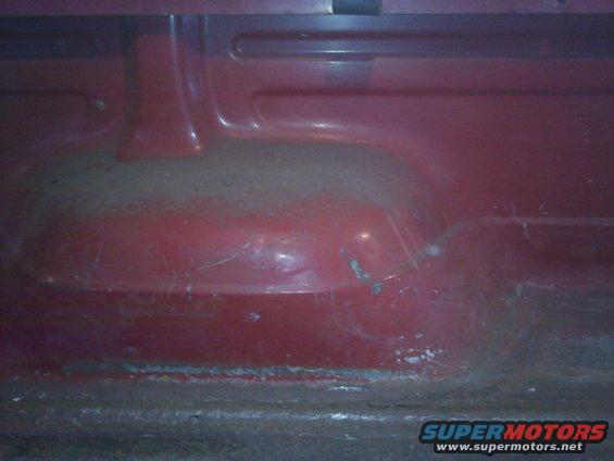 close-up of the red interior floor of a vehicle, showing some wear and tear