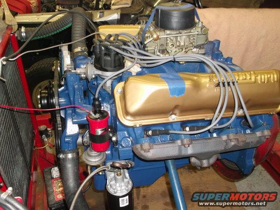 Ford V8 engine with gold valve covers and blue block, carburetor on top