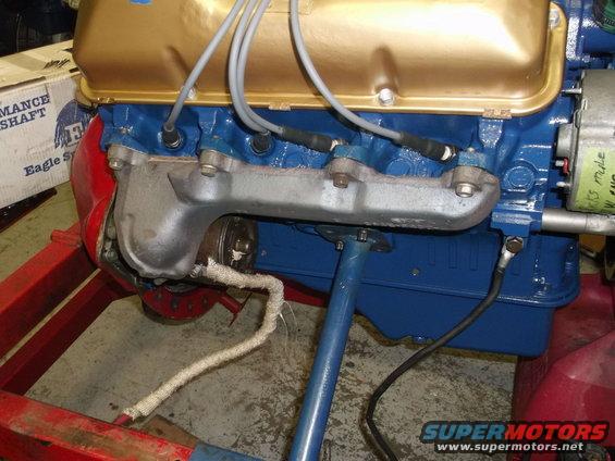 engine block with gold valve covers and blue paint, exhaust manifold attached