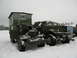 1987 Ford Bronco - Two military trucks are parked in a snowy landscape, with one truck's hood open and a trailer behind it.