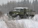 1987 Ford Bronco - A military truck navigates a snowy landscape with trees in the background.