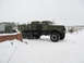 1987 Ford Bronco - A large green military truck with a flatbed and a trailer is parked in a snowy landscape.