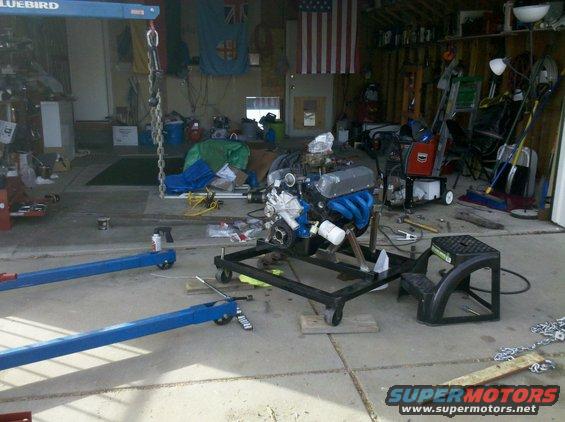 Engine on a stand in a garage with tools and equipment around