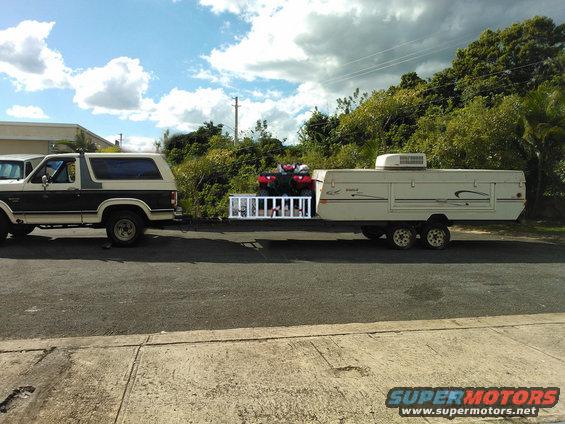 Ford Bronco towing a pop-up camper and an ATV on a ladder rack