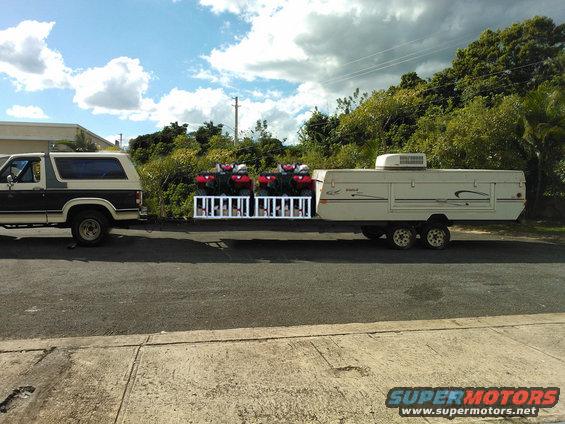 Bronco towing pop-up camper with four ATVs on the back
