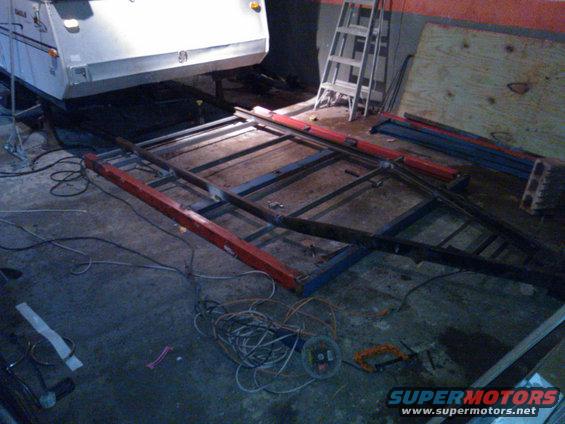 Trailer chassis under construction with metal beams and red supports
