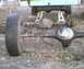 1984 Ford Bronco - Close-up of a vehicle's rear axle assembly, with a tire attached and the vehicle elevated on jack stands.