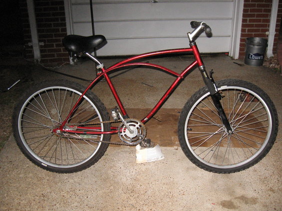 Red cruiser bicycle side view with wide tires and curved frame
