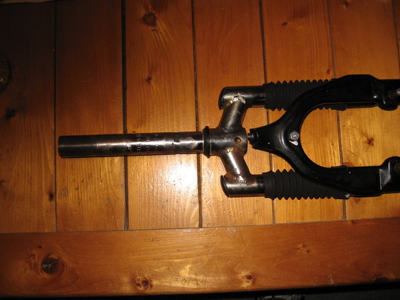 Black bicycle fork with metal steerer tube showing engraved text