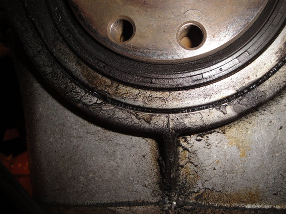 Close-up of a cracked and leaking engine seal with metal components visible