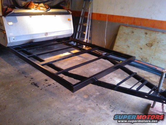trailer frame with a camper top attached, in a garage
