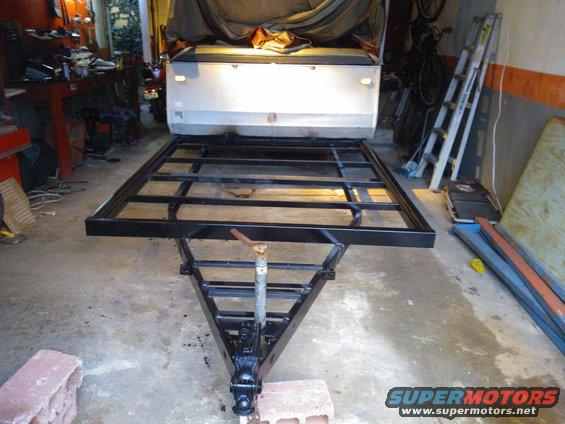 Trailer frame attached to the rear of a vehicle, in a garage