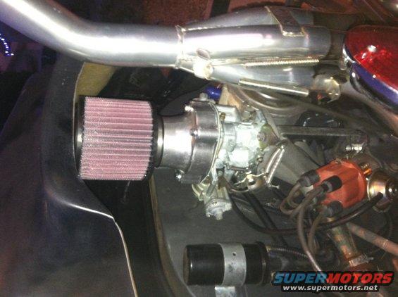 Engine bay with a large aftermarket air filter connected to the carburetor. Exhaust pipe is visible