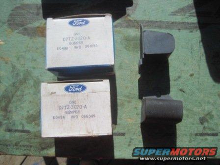 Two Ford boxes and a dark gray bumper part on a green surface