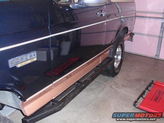 Side view of a 1995 Ford Bronco with a bronze stripe and running boards