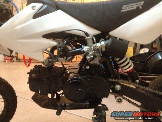 Motorcycle engine, white body panel, black seat with SSR logo, and rear suspension