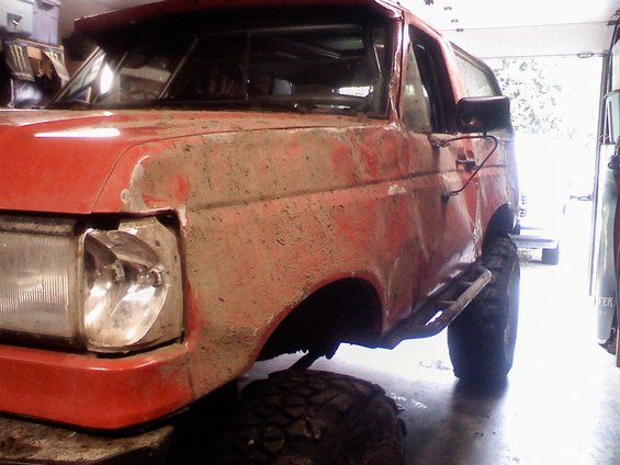 Red off-road SUV with mud splatter, front quarter view