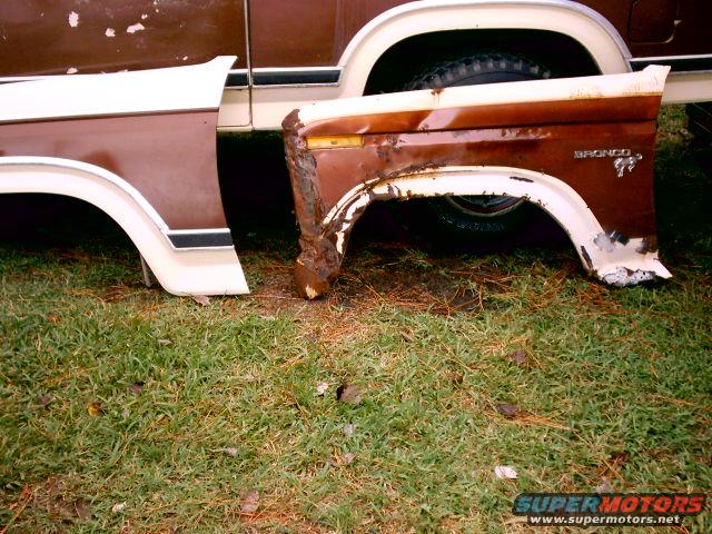 Rusty brown and white Ford Bronco fender removed from vehicle, showing significant rust damage