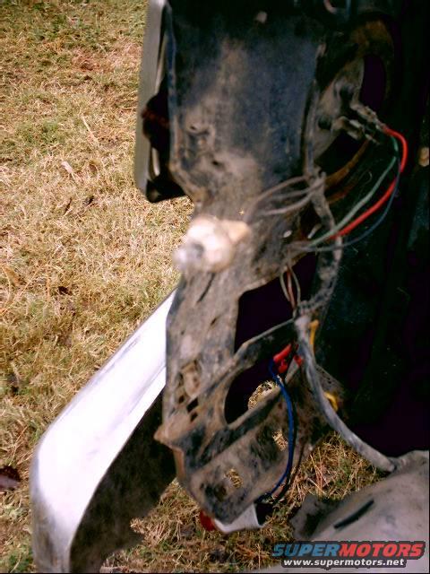 Close-up of a disassembled vehicle headlight assembly showing wiring and mounting bracket