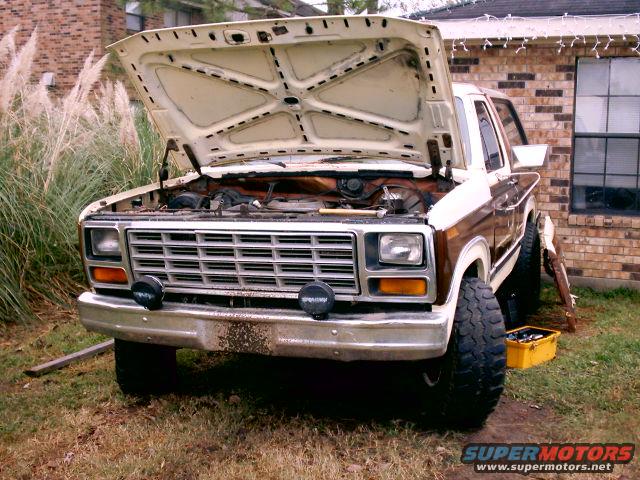 1980 Ford Bronco with hood open, front view, white and brown exterior, dirty bumper