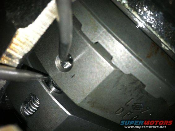 close-up of metal engine part with a screw being turned by a screwdriver